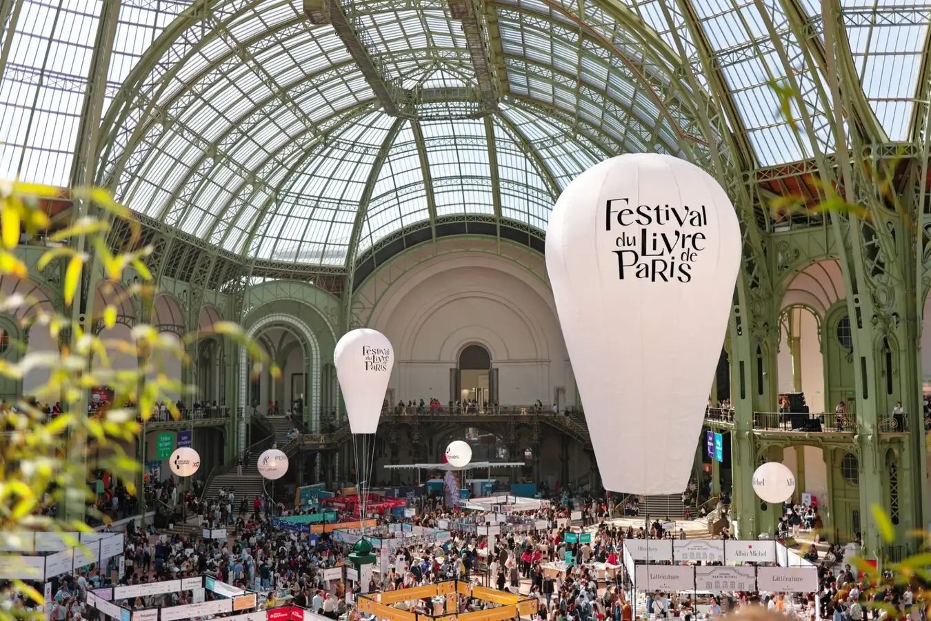 Nef du Grand Palais pendant le Festival du Livre de Paris, ballons blancs suspendus au-dessus des stands