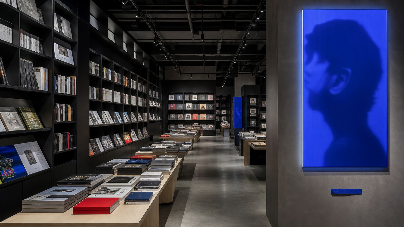 Librairie aux rayonnages noirs éclairée par un portrait rétroéclairé bleu